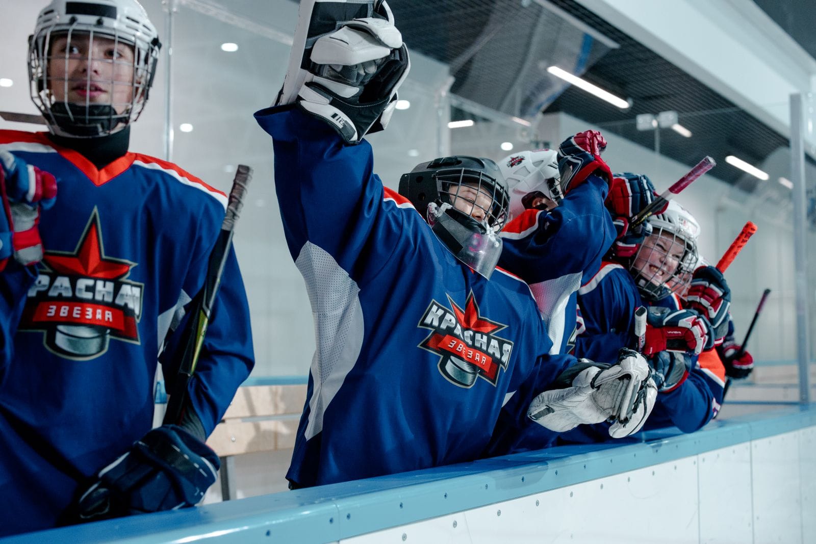 Youth hockey players in blue celebrating at the bench